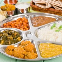 South Asian selection of vegetarian curries served in a traditional dish with rice, chapatis, poppadoms, yoghurt and chili sauce.